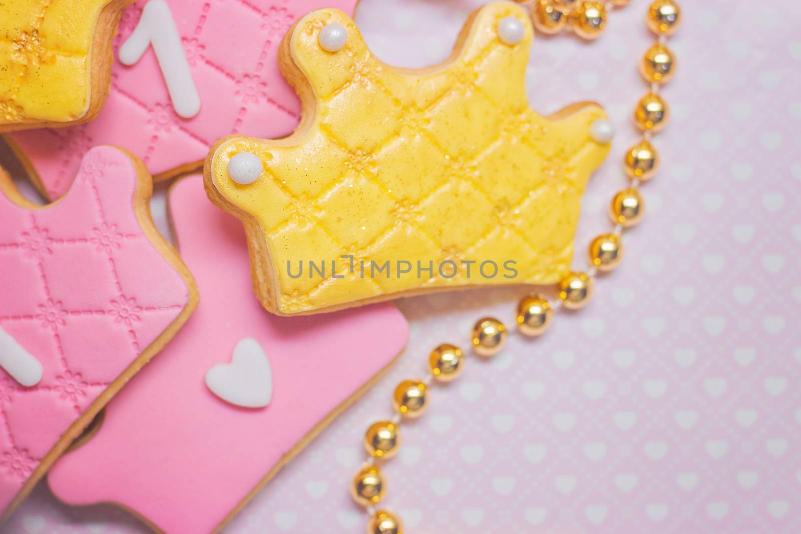 First birthday, crown shaped royal icing cookies on pink background