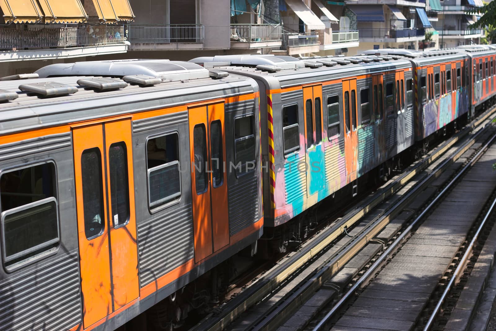 Suburban commuter passenger train entering station in sunny day.