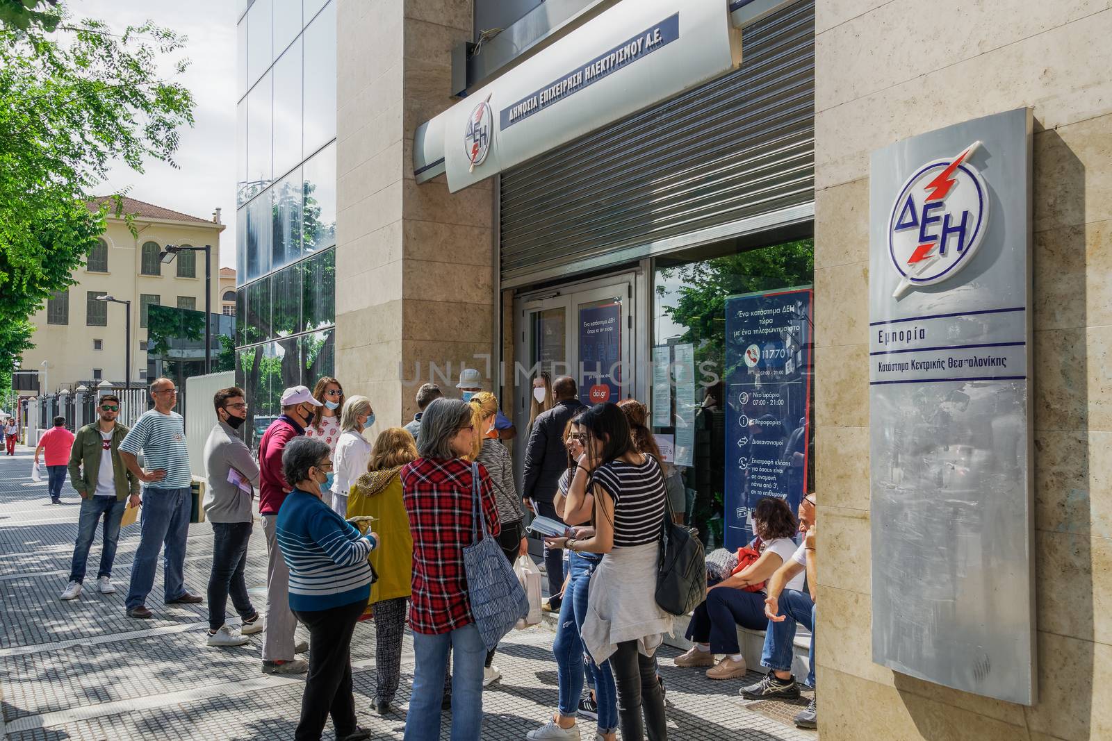 Greeks keep distance outside DEI-Public Power Corporation for electricity store, in line with decision to prevent COVID-19.