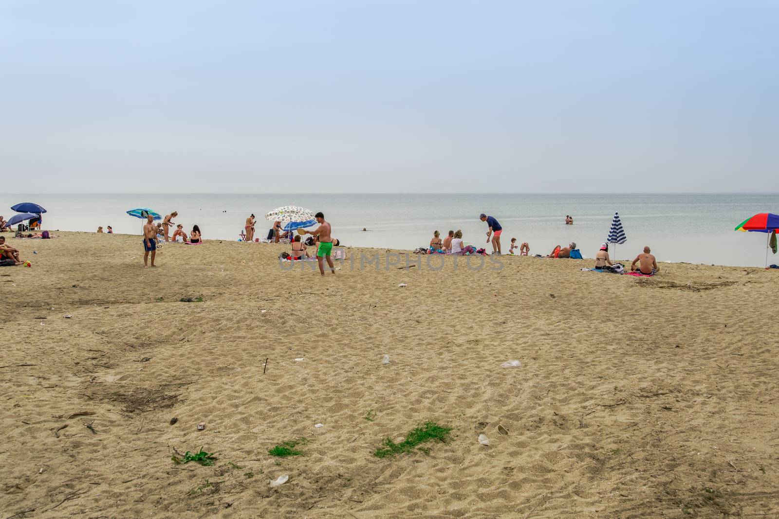 Bathers with sun umbrellas on sand by the sea at Thessaloniki suburbs, after government suggests people keep a distance.