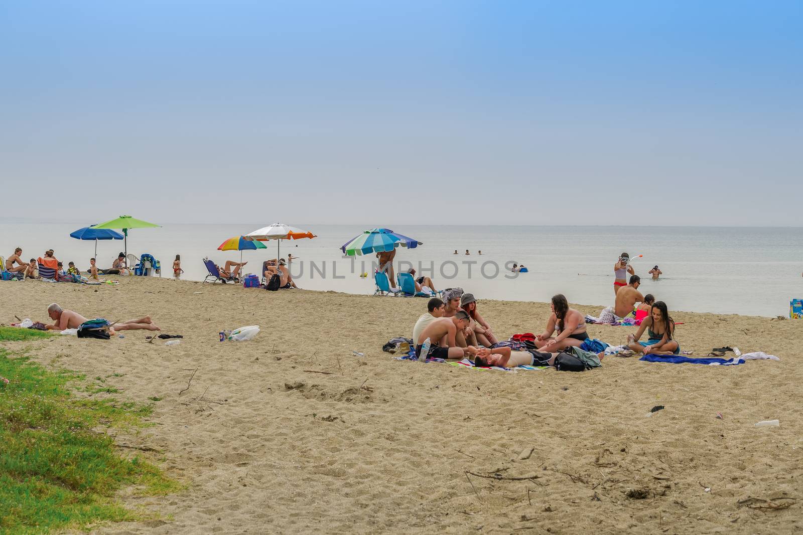 Bathers with sun umbrellas on sand by the sea at Thessaloniki suburbs, after government suggests people keep a distance.