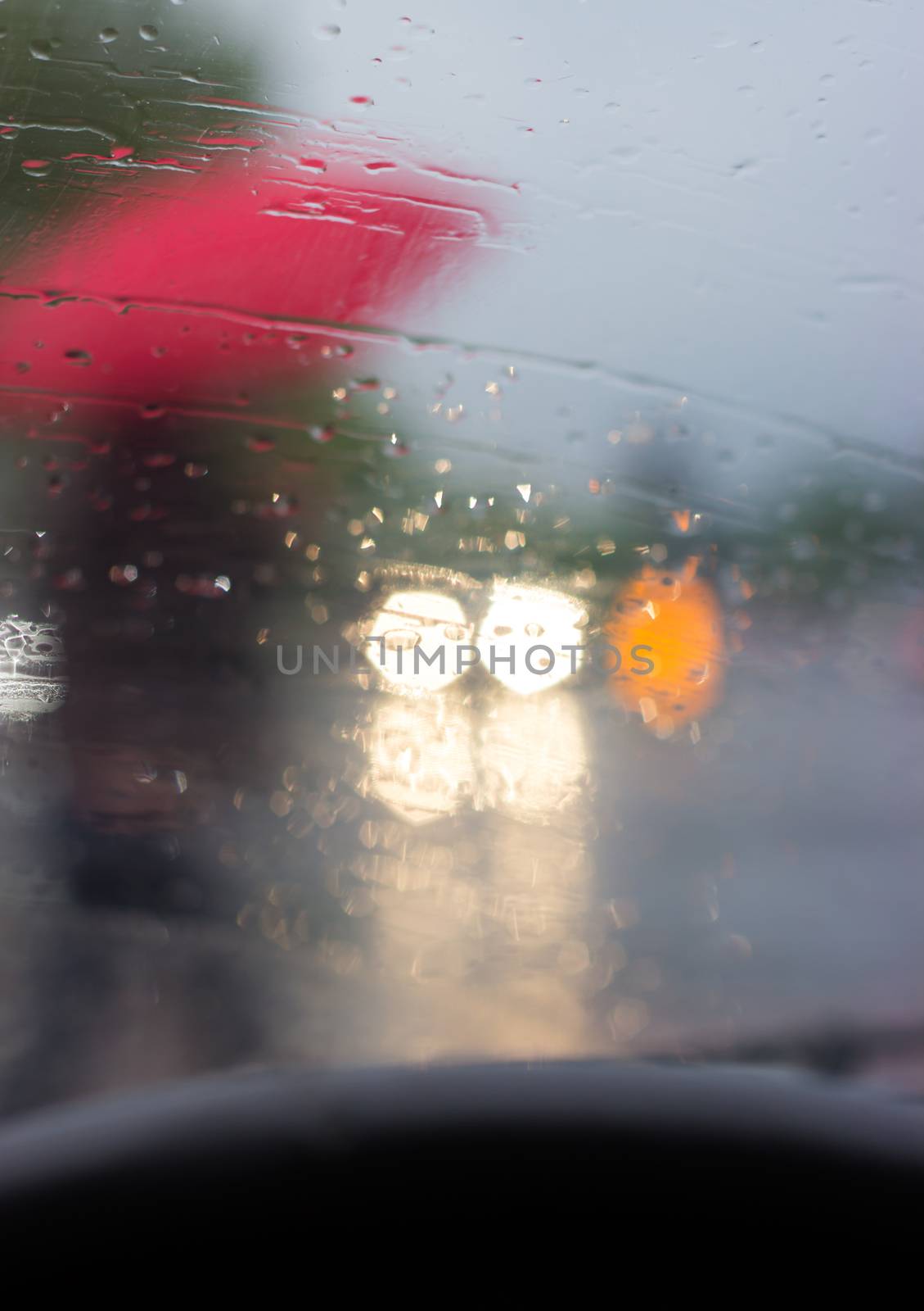 Behind the wheel - silhouette of a man with red umbrella, picture taken from the car, behind windshield