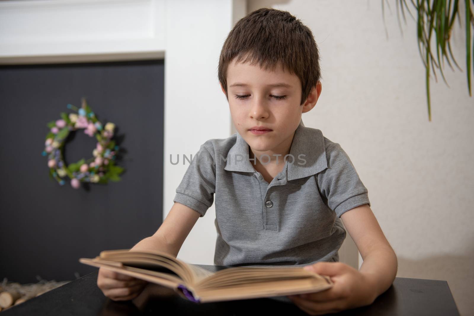 A schoolboy without expressed interest reads a book by marynkin