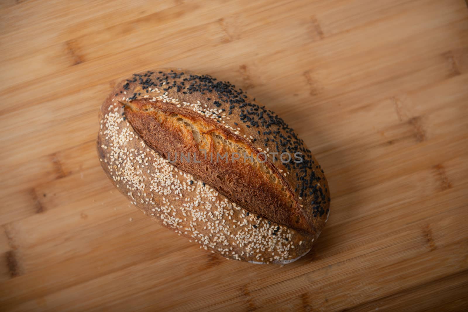 craft bread is sprinkled with white and black sesame seeds on a wooden background with copy space by marynkin