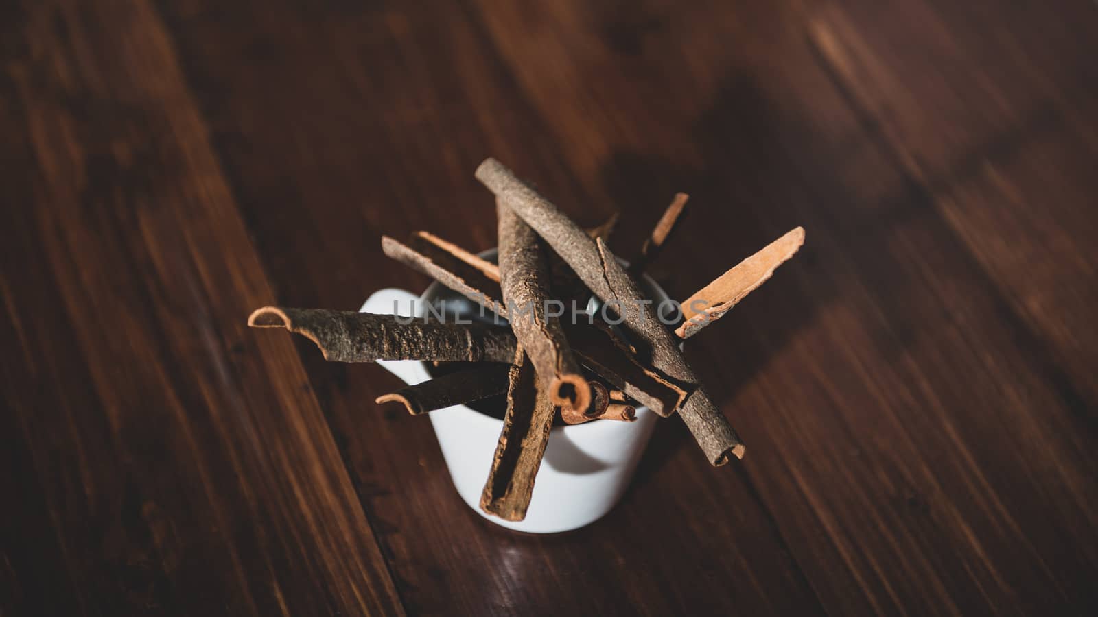 Top view of cinnamon on a white cup on a wooden background by marynkin