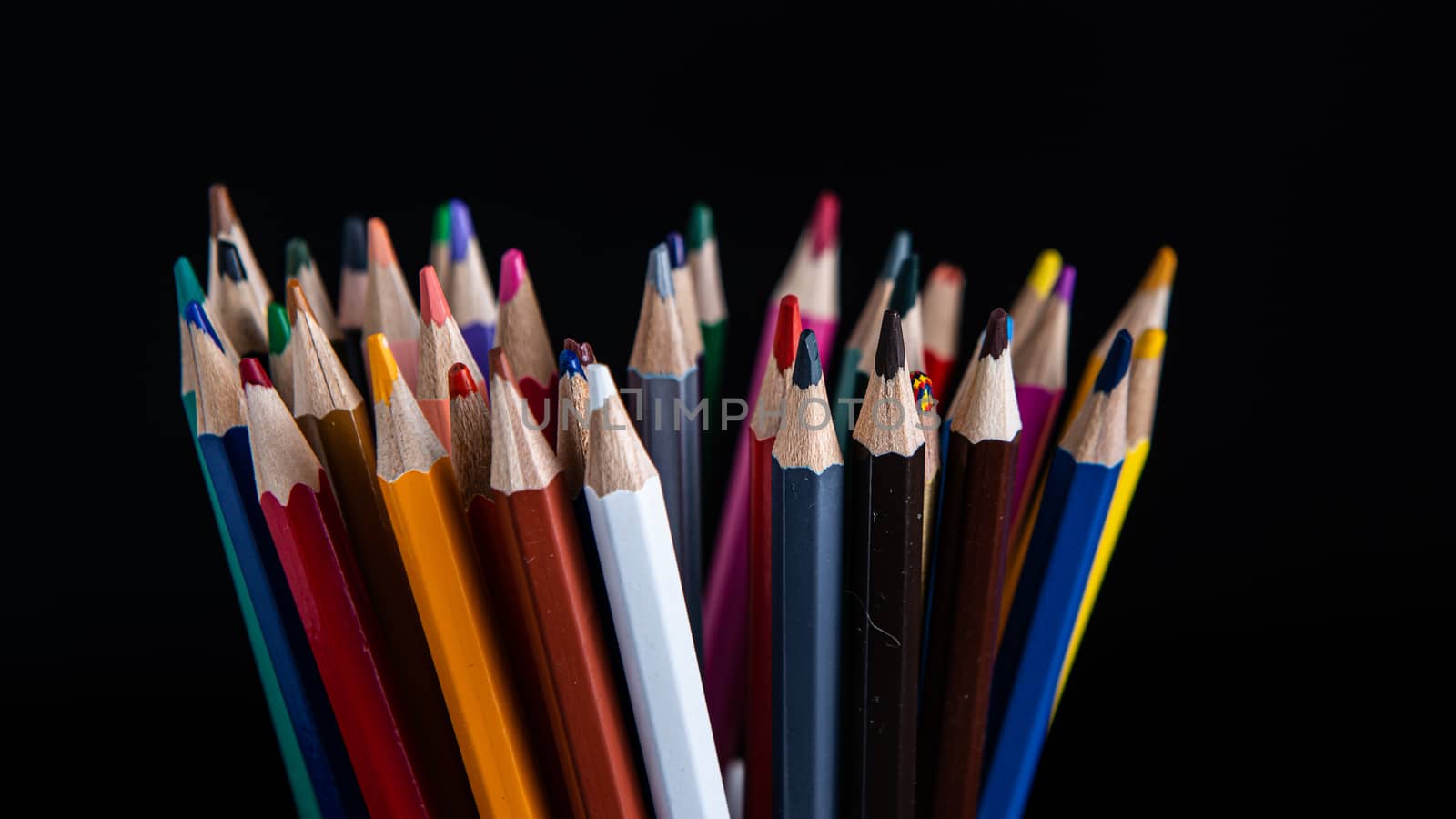 colored pencils on a black background with copy space by marynkin