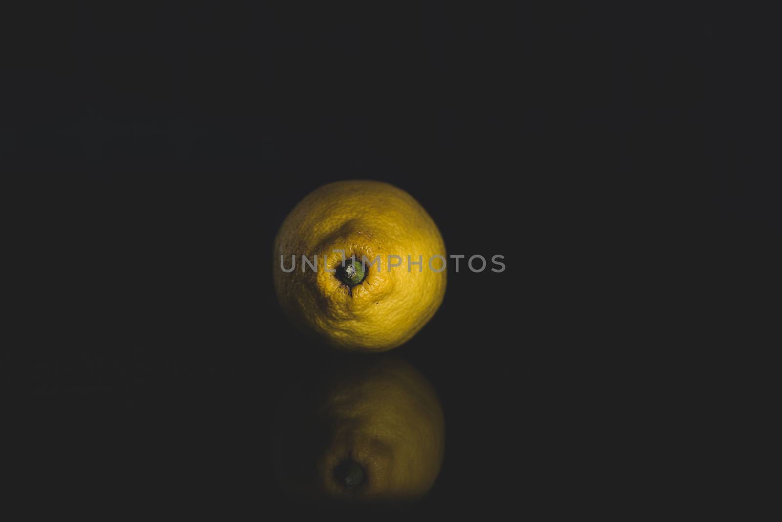 portrait of a lemon on a black background with reflection and copy space by marynkin