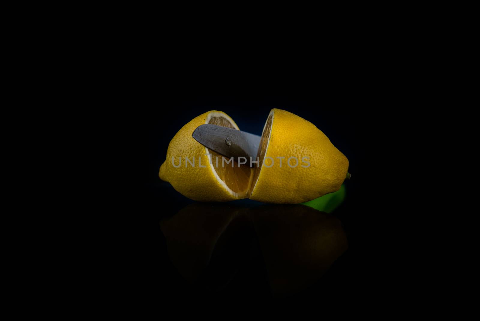 two halves of lemon cut with a knife on a black background with copy space
