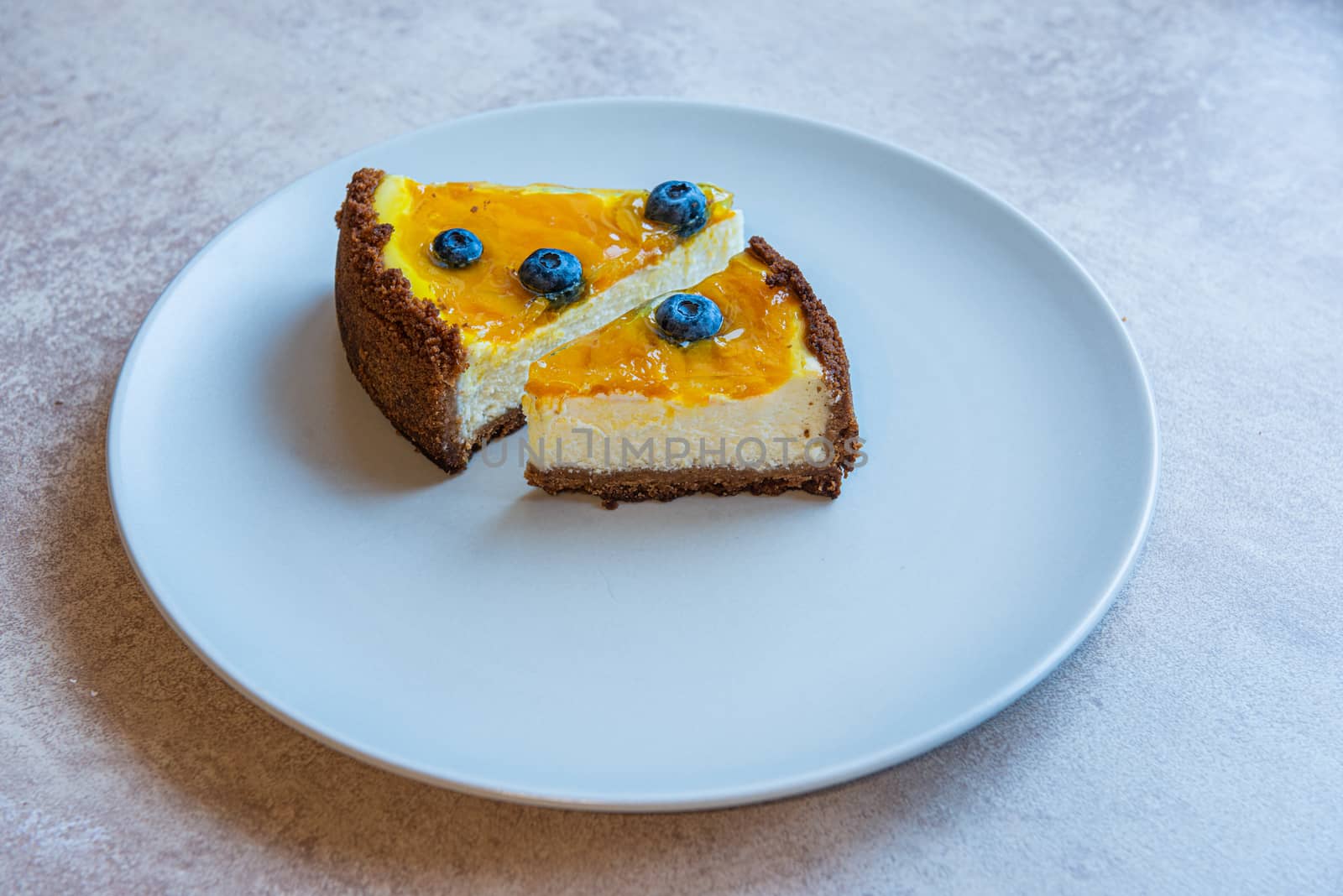 Grey plate with two pie of homemade cake with berry decorate on top by marynkin