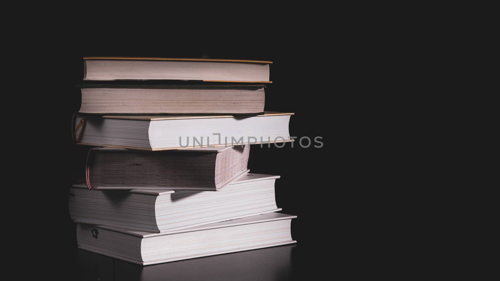 High messy stack of books on a black background with space for text message. by marynkin