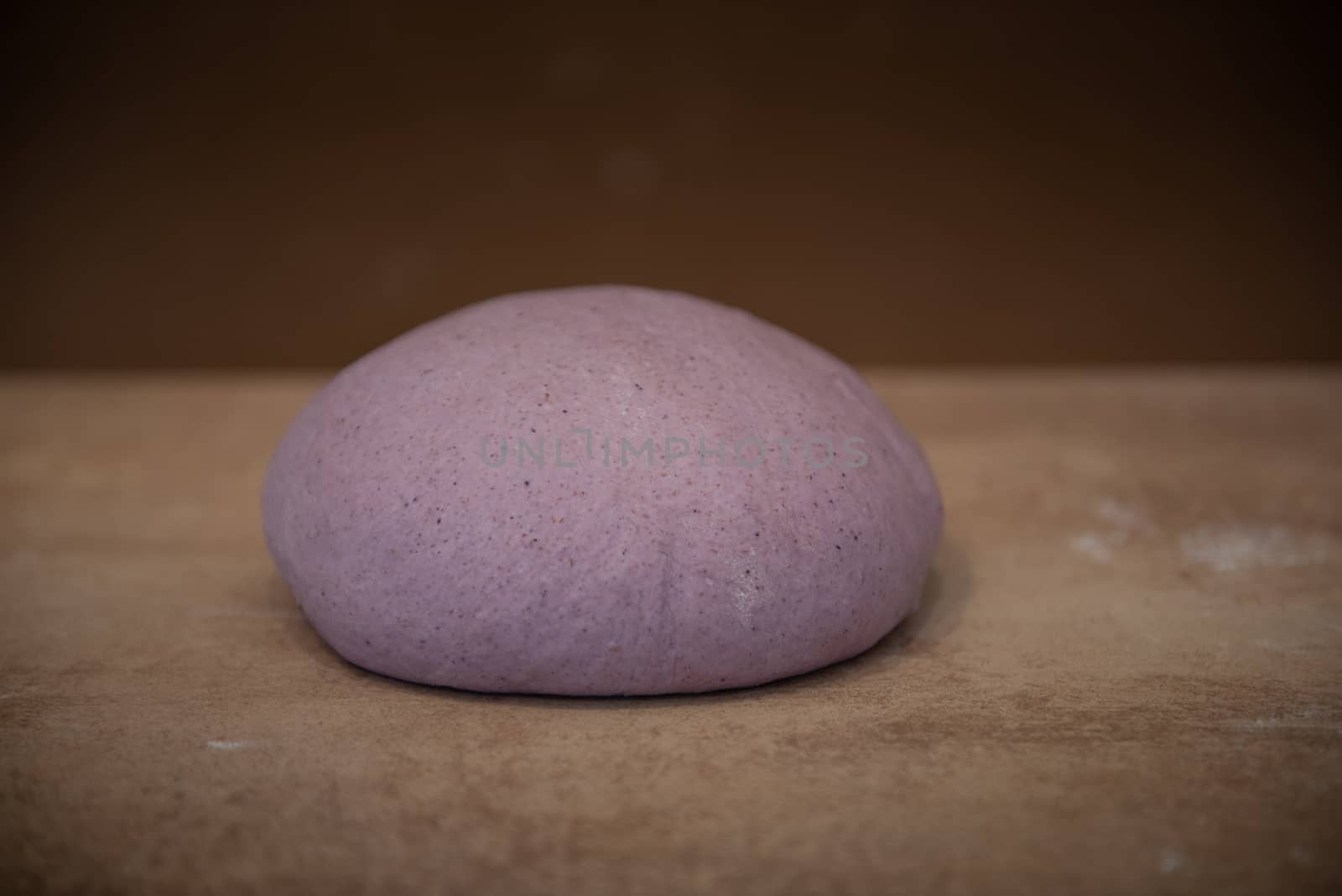 Preparation for bread unusual lilac-colored dough on a brown background