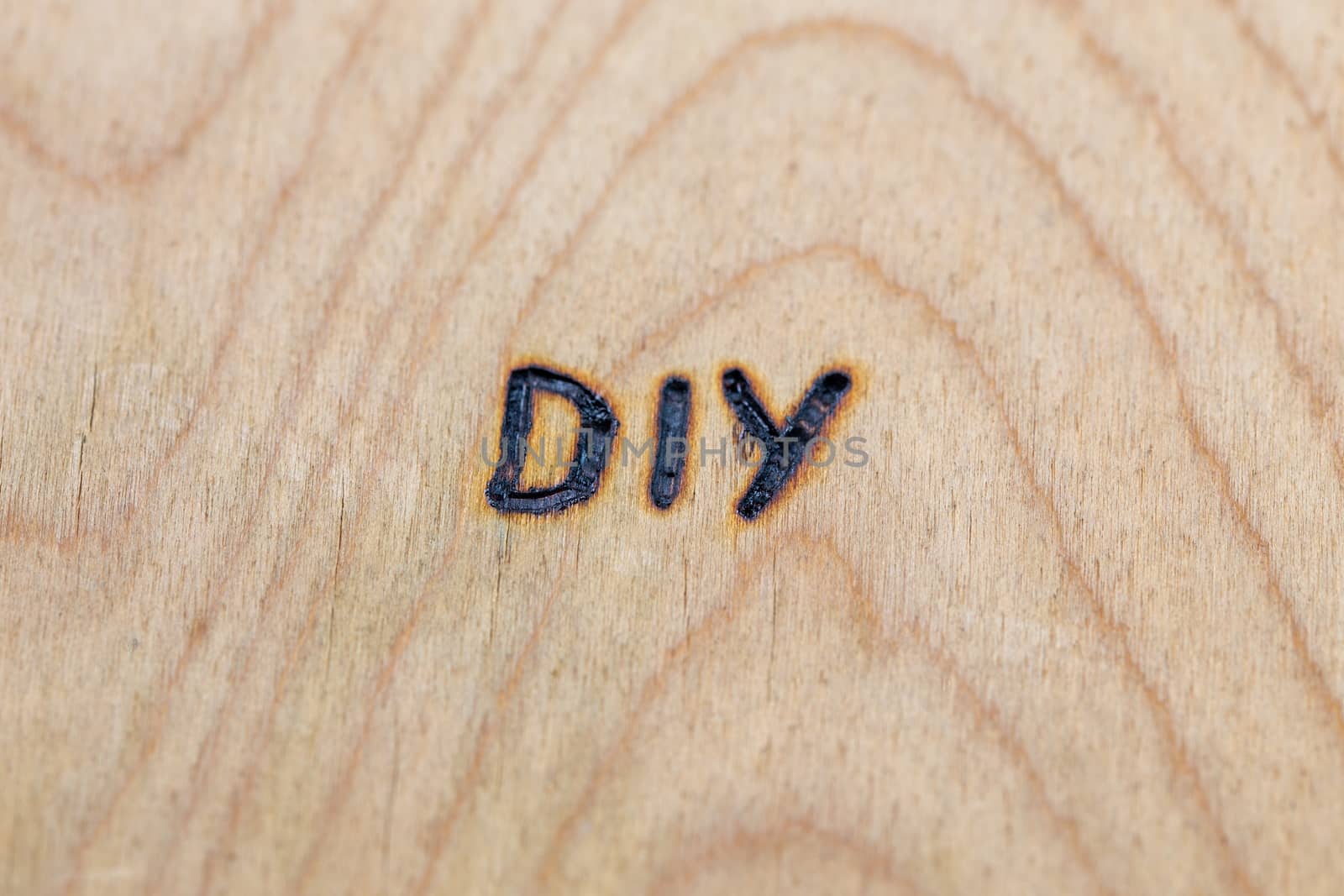 an abbreviation DIY - do it yourself - burned by hand with electrical woodburner on plywood surface.