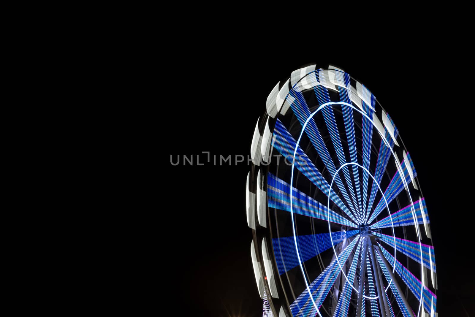 Long exposure of ferris wheel illuminated at night by marynkin