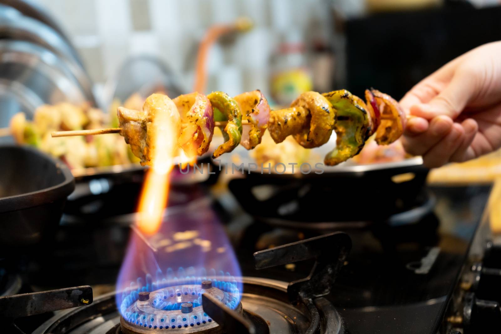 Macro selective focus shot of cottage cheese, onions, mushrooms and more on a wooden skewer roasted over an open flame to char it by Shalinimathur