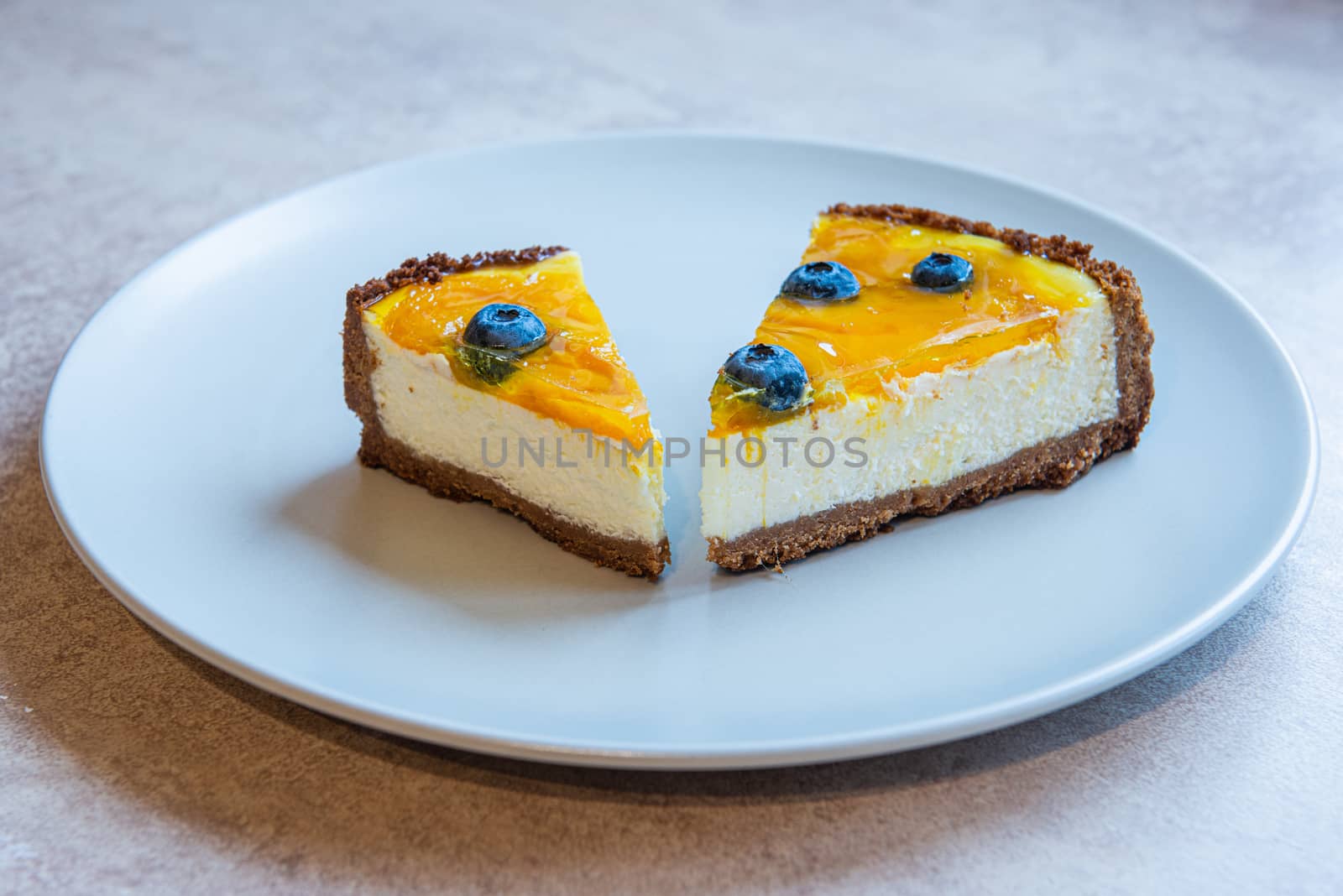 Two piece of homemade cake on grey plate with berry decorate on top