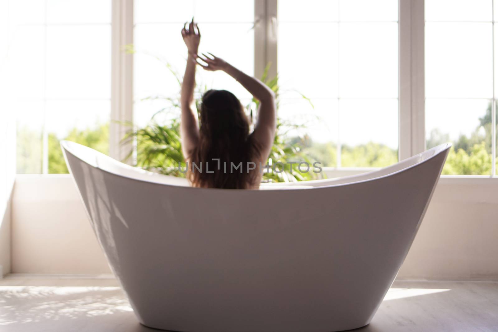 An Attractive girl relaxing in bath on light background. Blurred photo by natali_brill