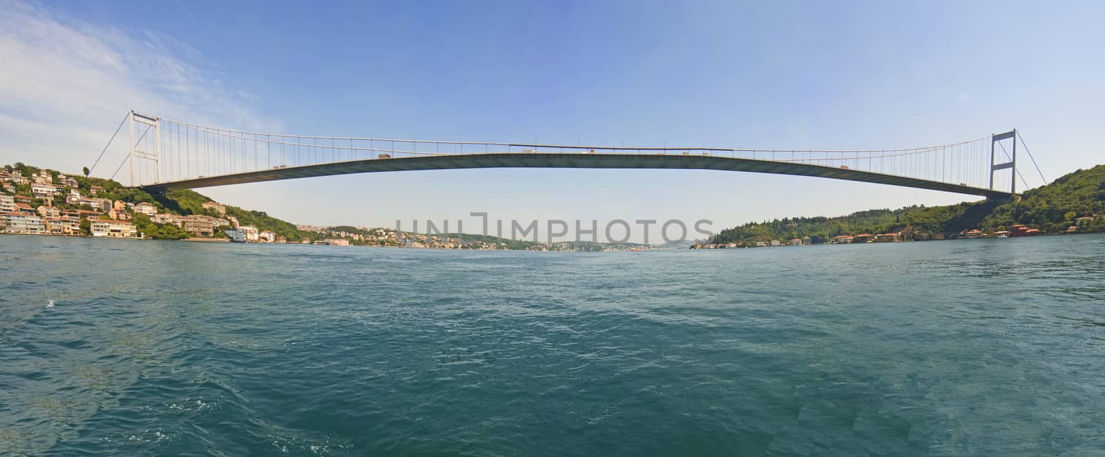 Ataturk suspension bridge spanning the Bosphorus river in Istanbul, Turkey against a blue sky