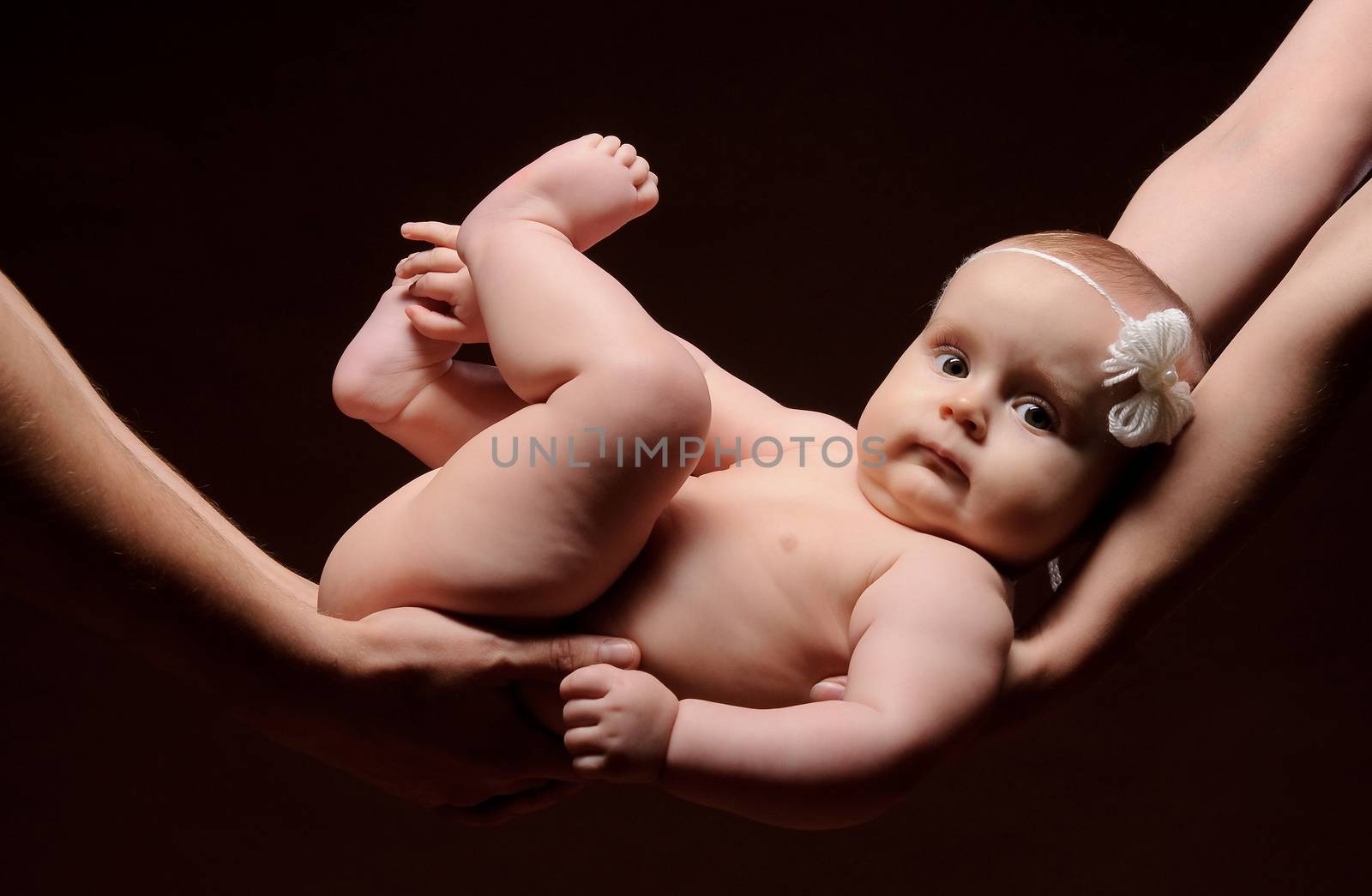 Male and female holding nice infant baby girl. Daughter on father's and mother's arms. Human growth and development. New generation. New life concept. Dark background