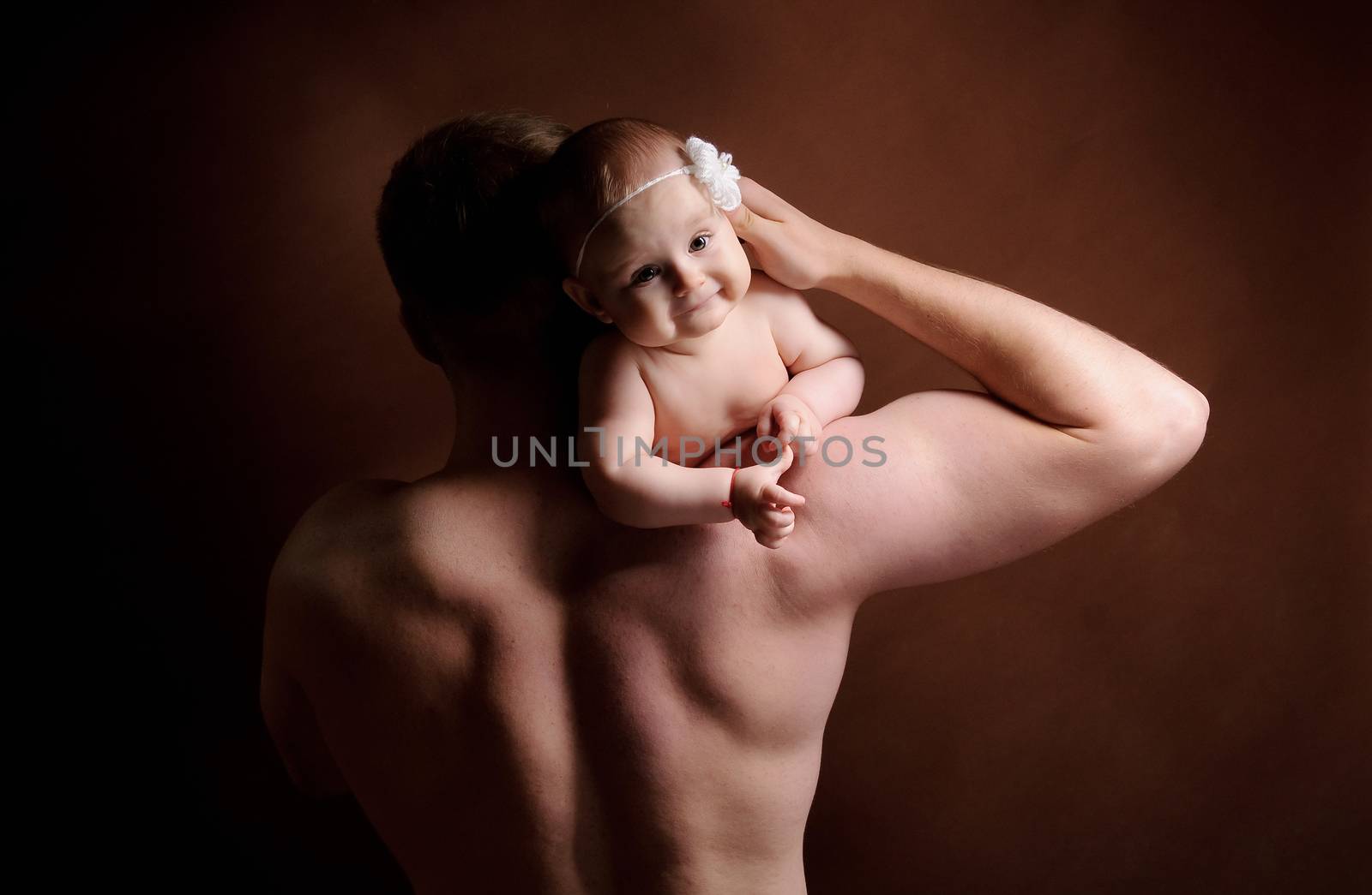Male holding nice infant baby girl. Daughter on father's shoulders. Human growth and development. New generation. Cheerful man and his baby. New life concept. Dark background