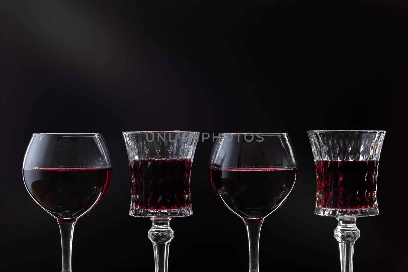 Rose wine. Red wine in four wine glasses over dark background with rays of light.