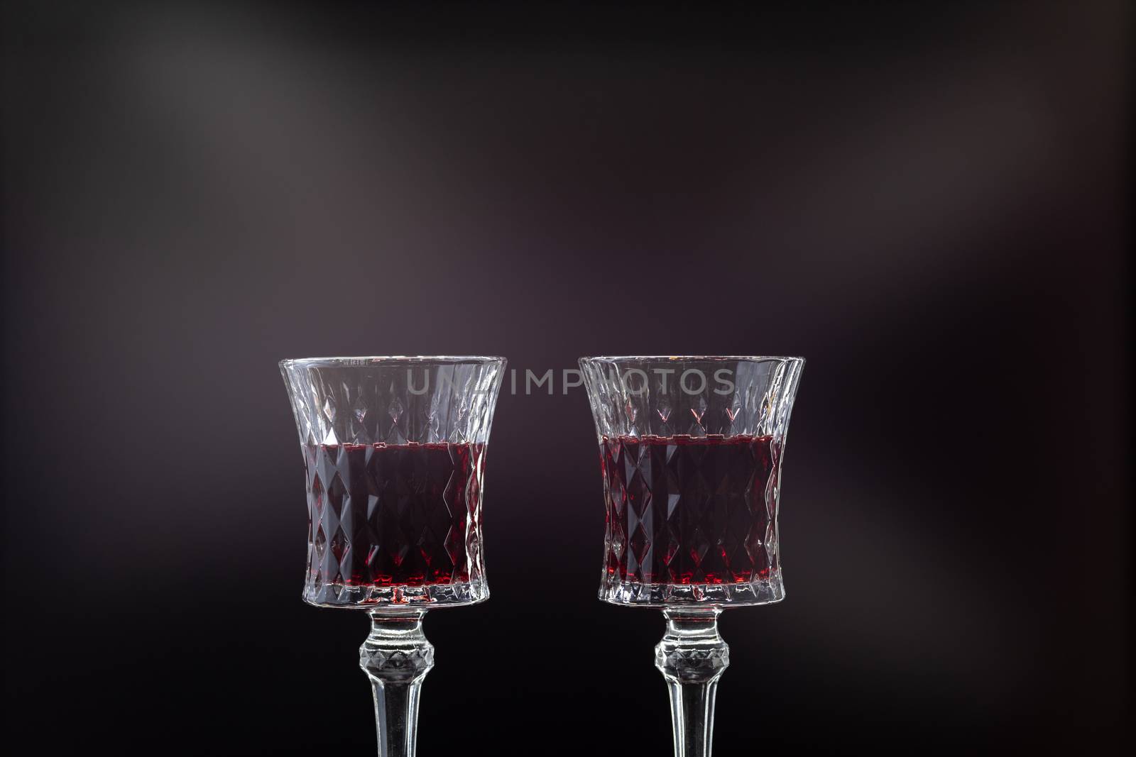 Rose wine. Red wine in two wine glasses over dark background with rays of light.