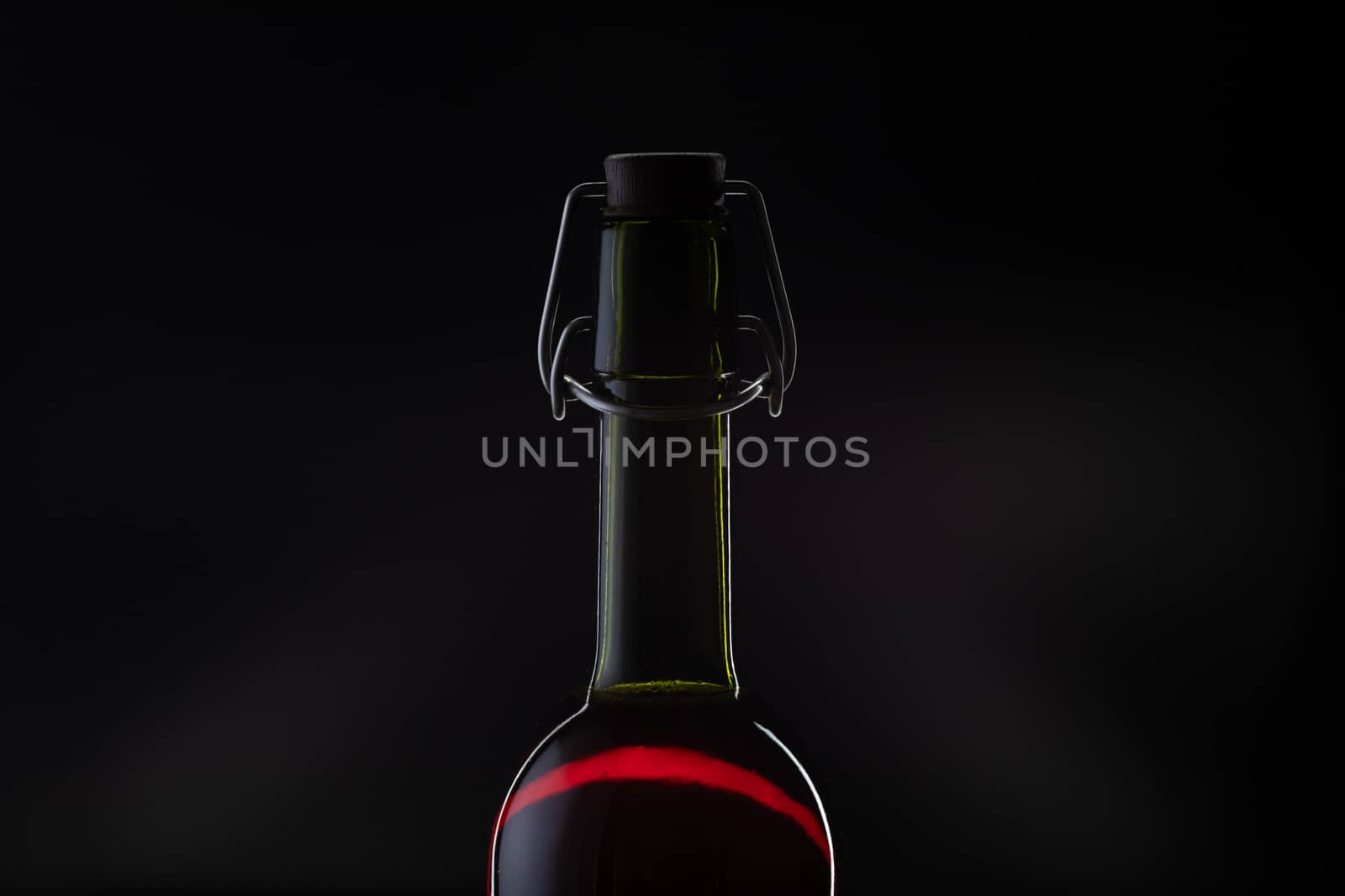 Rose wine. Red wine in bottle and metal opener on cork. Dark background. Silhouette
