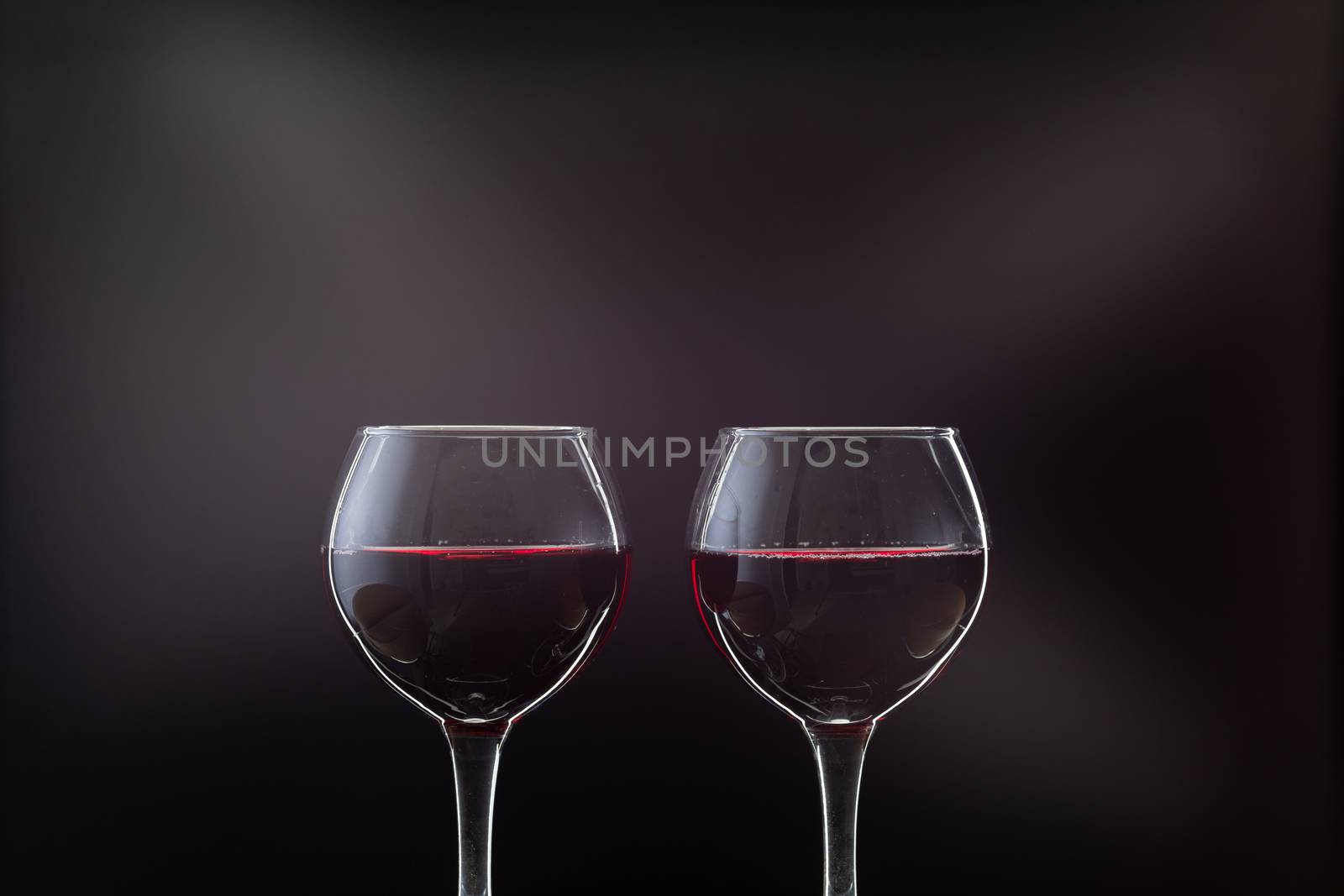 Rose wine. Red wine in two wine glasses over dark background with rays of light.