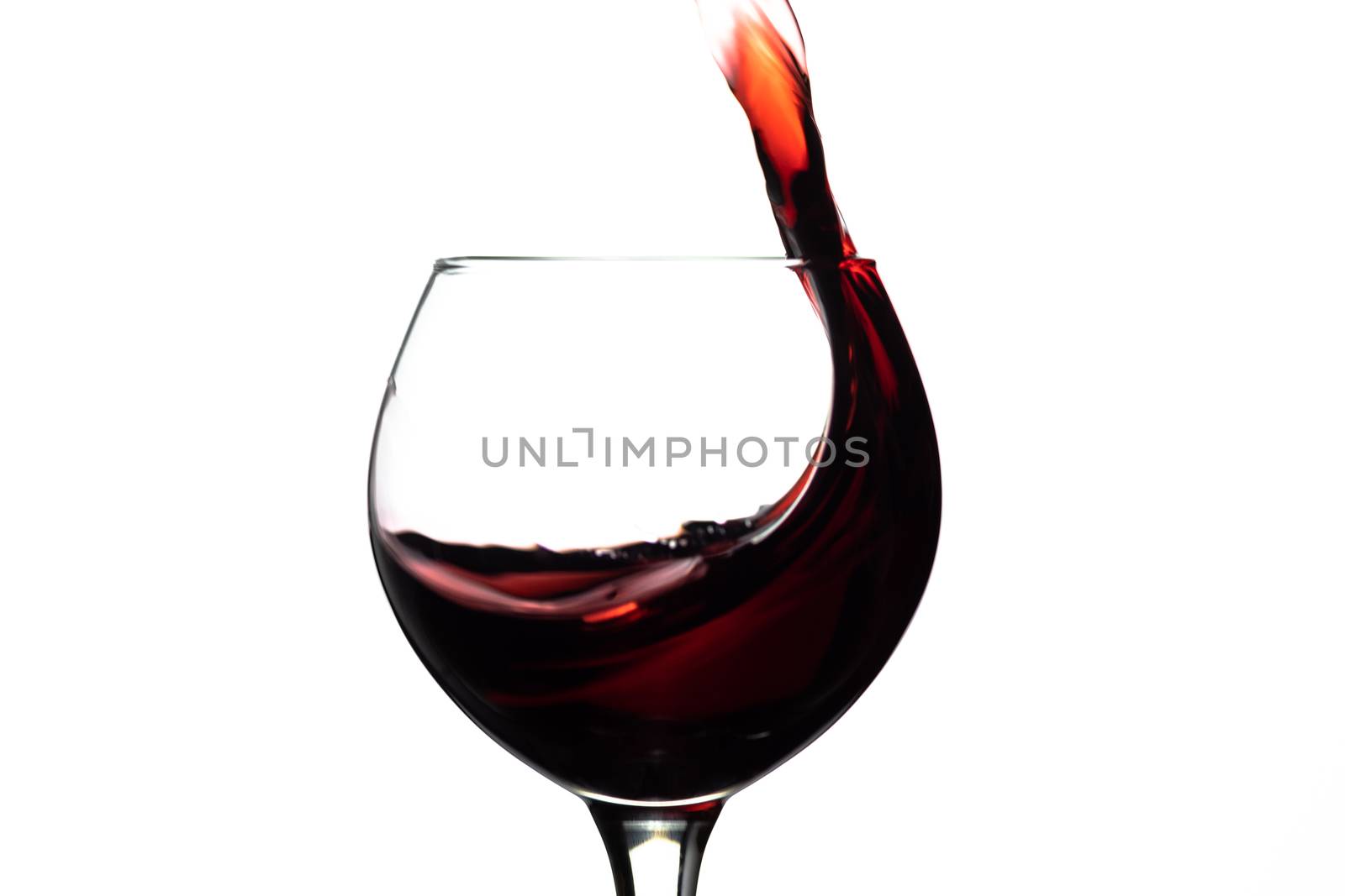 Red wine splash into glass on white background.