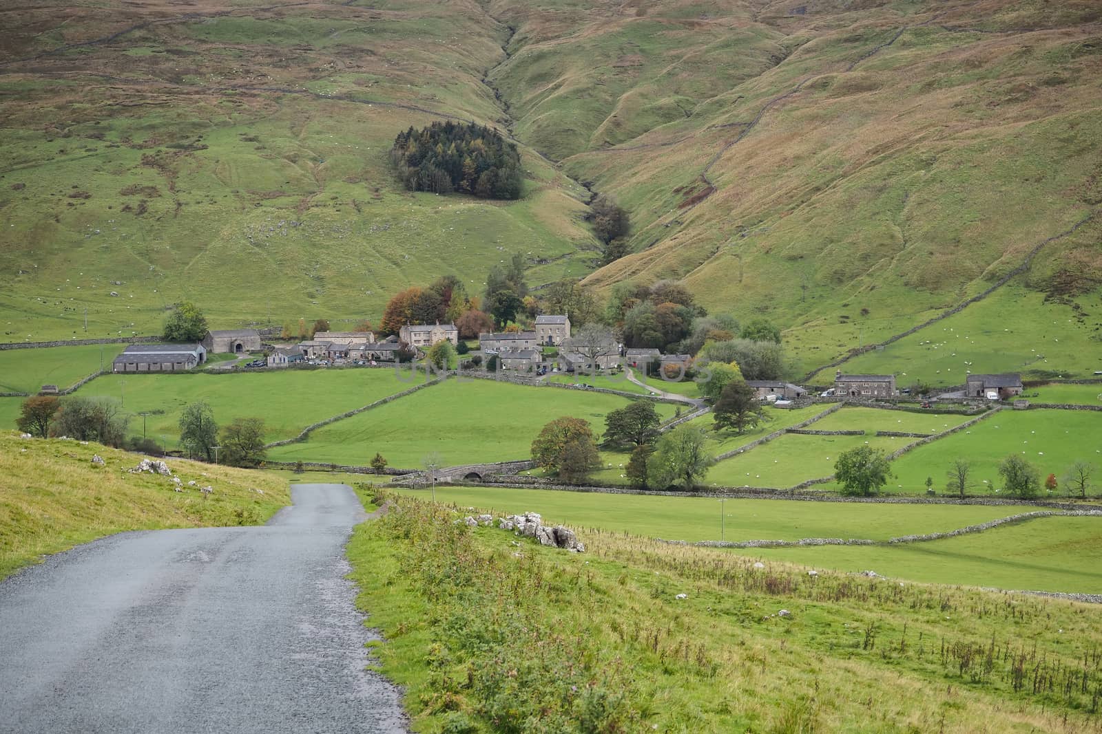 Looking down the road to the picturesque village of Halton Gill nestling in the hillside, Yorkshire Dales, UK