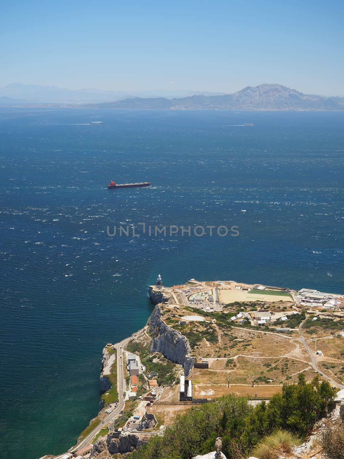 View from the top of the Rock of Gibraltar across the Strait of Gibraltar with passing container ship and Morocco in the distance