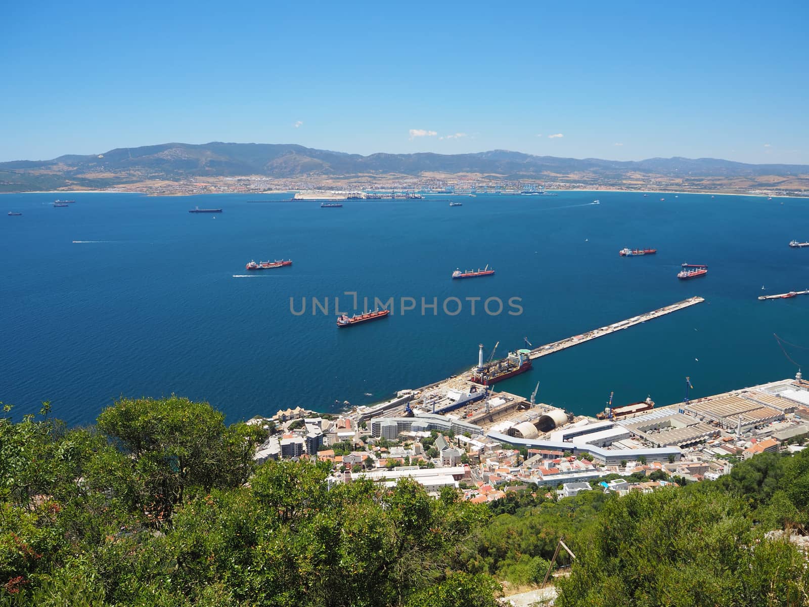 Container and cargo ships around the Rock of Gibraltar with the port of Algeciras, Spain, in the background