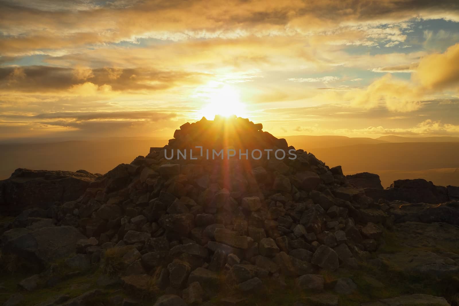 Stunning sunset over the cairn at the rocky outcrop at the top of Great Whernside overlooking Wharfedale, Yorkshire Dales, UK