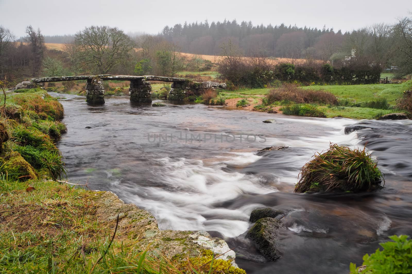 Fast flowing water under the 13th century stone clapper bridge originally built to enable pack horses to cross the East Dart River at Postbridge, Dartmoor National Park, Devon, UK