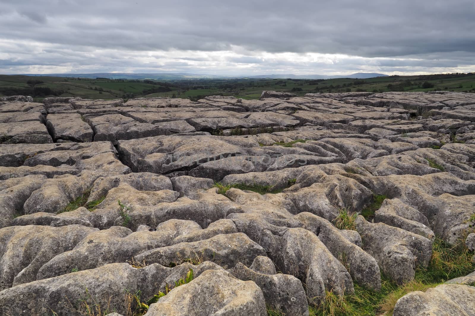 The dramatic fissured limestone pavement geology high above Malham Cove set against a moody overcast sky, Yorkshire Dales, UK