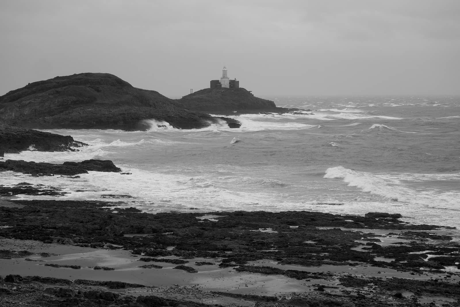 Mumbles Lighthouse lit up on a stormy day overlooking Bracelet Bay, shot in monochrome, the Gower Peninsula near Swansea, South Wales