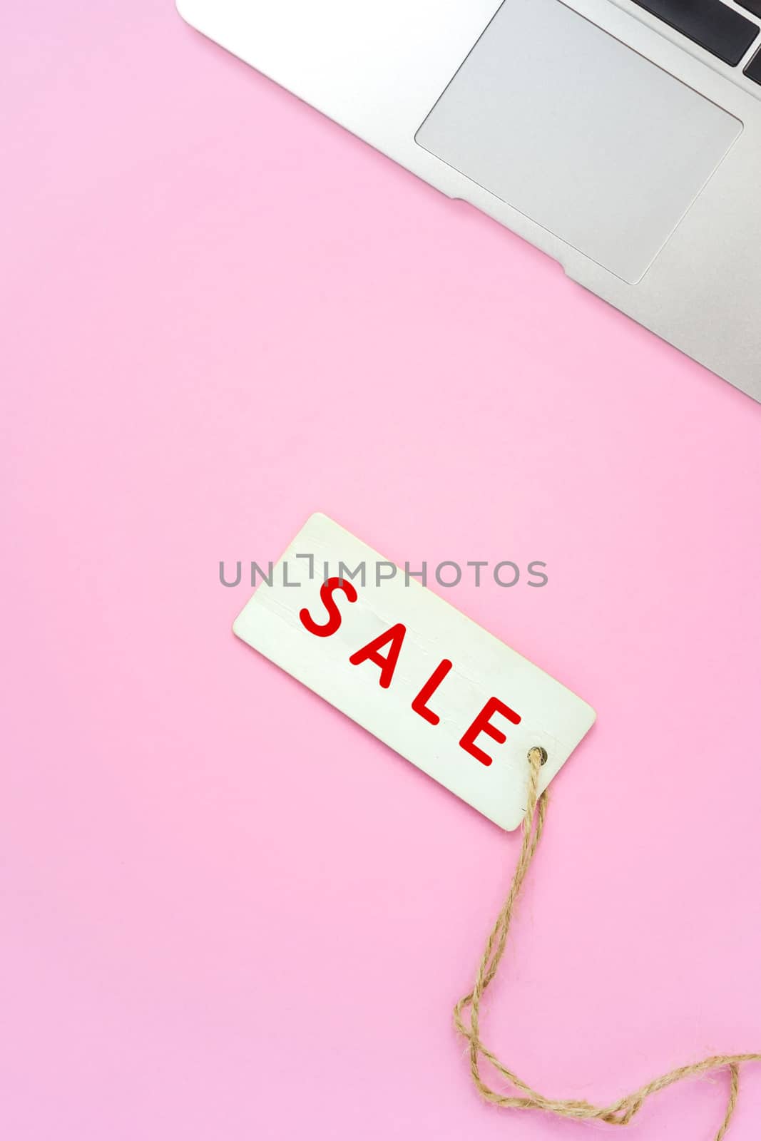 Sale tag and laptop on pink background, online shopping concept