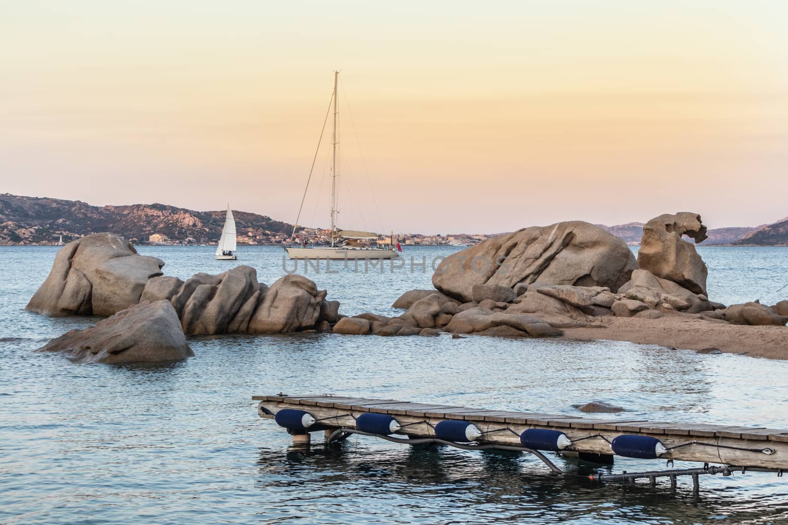 Sailboat sailing by beautiful rocky formations on the Spiaggia di Punta Nera beach. Luxury summer adventure, active vacation in Mediterranean sea, Costa Smeralda, Sardinia, Italy.