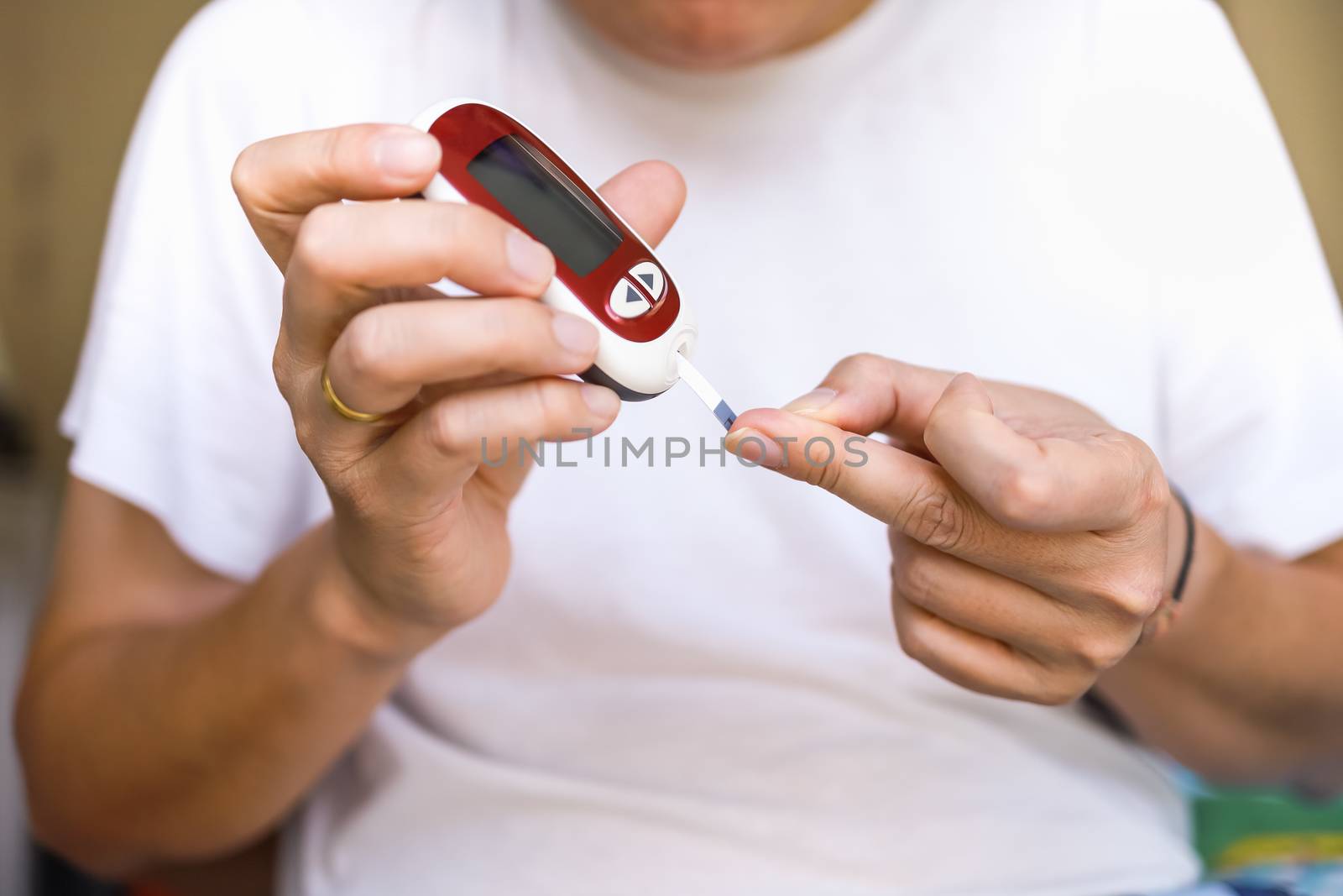 Close up of man hands using Glucose meter on finger to check blo by mthipsorn