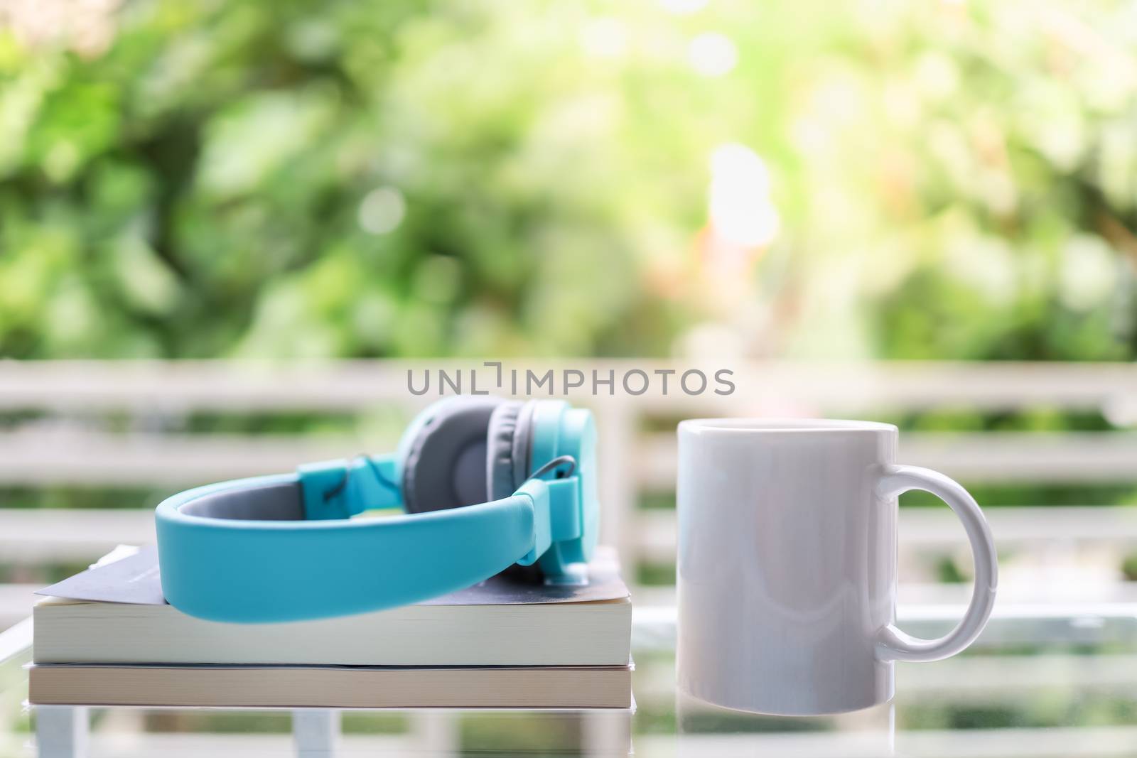 Hobby, Relaxation and Recreation Concept. Close up of white mug cup of hot coffee with headphone and books in garden with copy space.