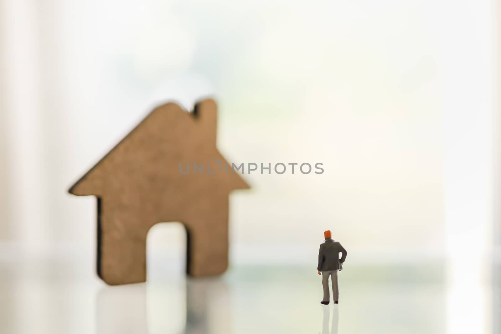 Business, Shelter in Place, Stay and Work at home and family Concept for Coronavirus 2019 (COVID-19). Businessman miniature figure people standing with wooden house icon on table with copy space.