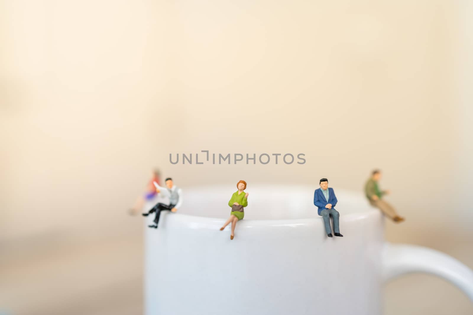 Business, Social Distancing concept for coronavirus 2019 disease  (COVID-19)  situation . Group of businessman and woman miniature sitting on white mug of hot coffee with copy space.