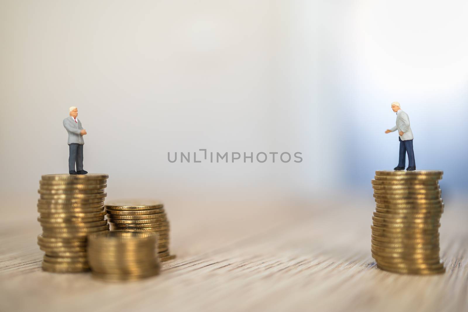 Business, Social Distancing Coronavirus, Covid-19 Protection Concept.  Two businessman miniature figure people standing on stack of gold coins on wooden table.