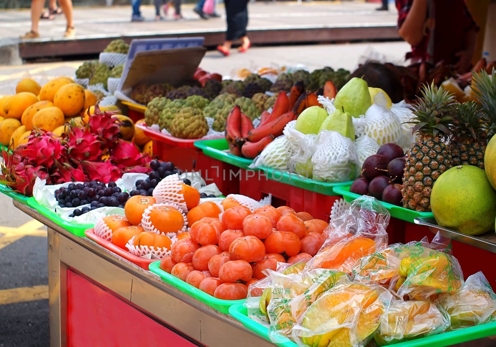 An outdoor fruit stall with guavas, grapes, dragon fruit, mangos, custard apples and other fruit