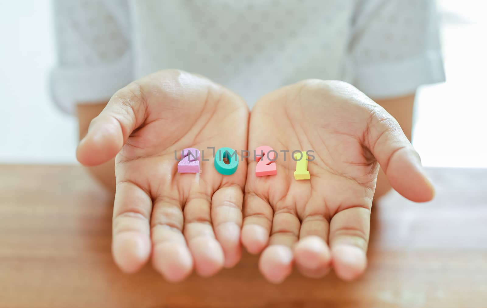 2021 New Year Planning and target Concept. Close up of colorful wooden number on woman hand on wooden table.