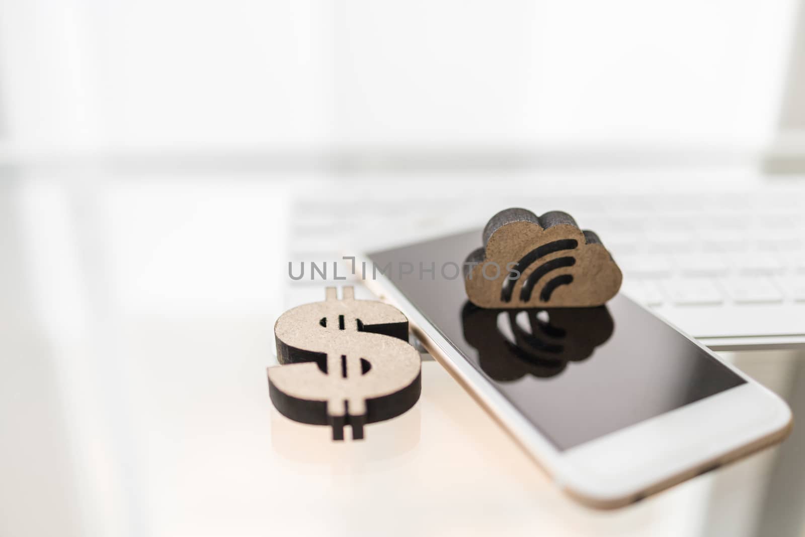 Business, Money, Finance, Communication and work Concept. Close up of wooden dollar sign icon with mobile smartphone and cloud icon with computer keyboard.