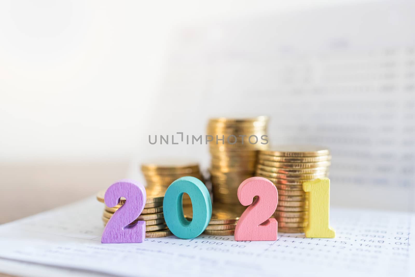 2021 New year, Business, Saving and Planning Concept. Close up of colorful wooden number on bank passbook with stack of gold coins with copy space.