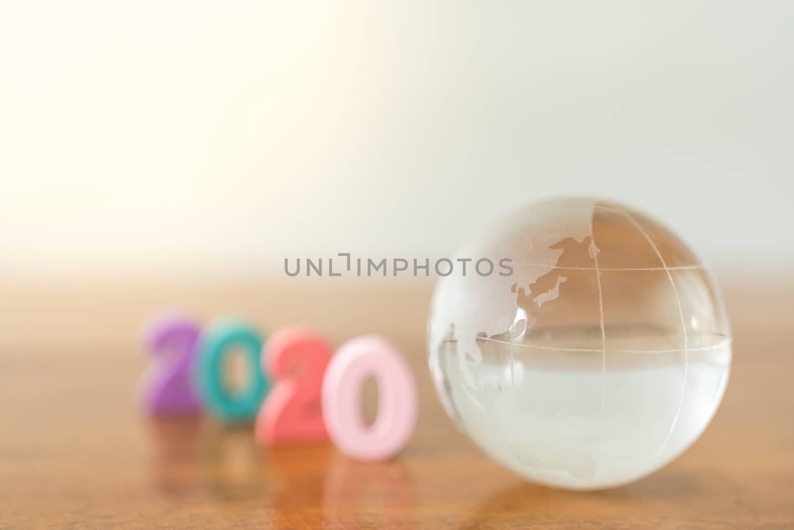 World Economy and 2020 business planning concept. Close up of glass mini world ball with colorful wooden number on wood table with copy space.
