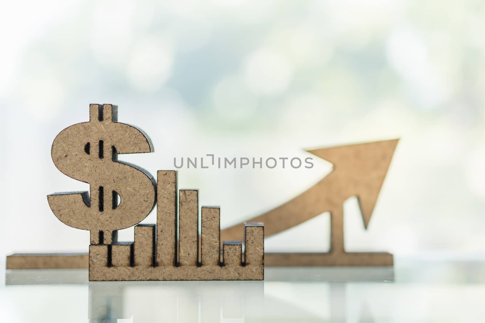 Business, Money, Finance Growth and planning Concept. Close up of wooden dollar sign and bar chart graph and arrow with copy space.