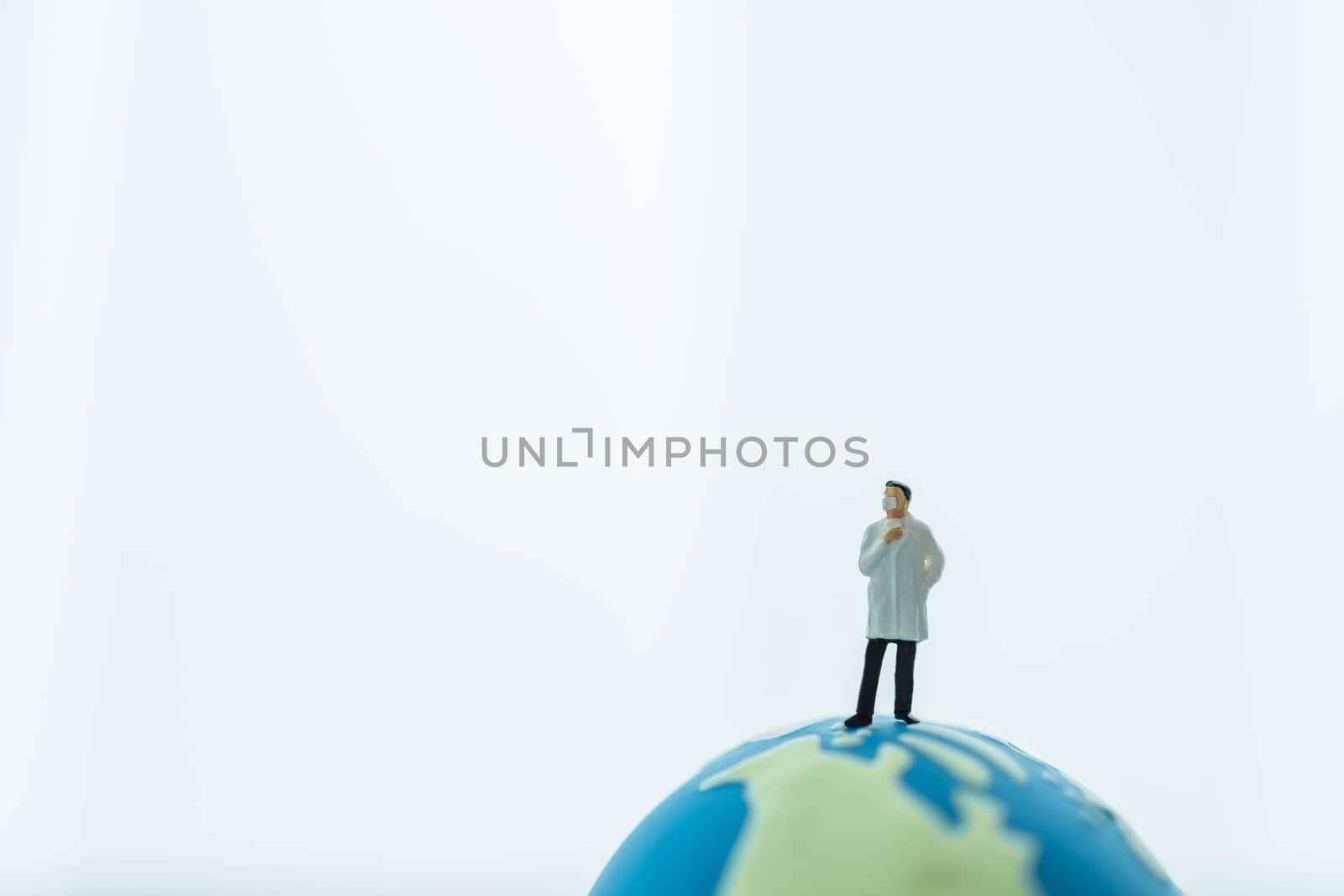 Global Healthcare, Coronavirus, Covid-19 Protection Concept. Doctor miniature figure people wearing surgical  face mask standing on mini world ball on white background and copy space.