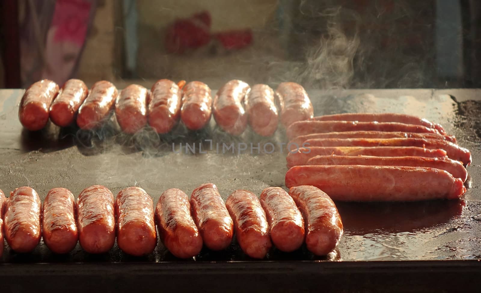 An outdoor vendor roasts fresh pork sausages on a grill
